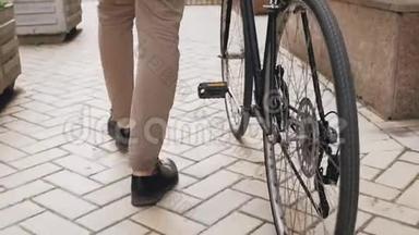 低角度慢动作镜头时尚男子与老式运动自行车行走在街道与铺砌的道路
